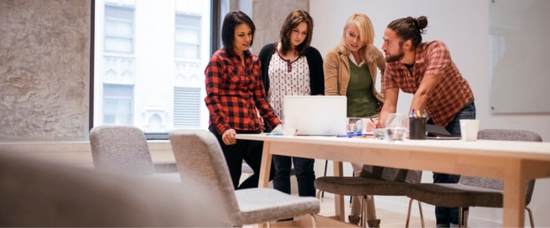 Team sharing knowledge around a laptop