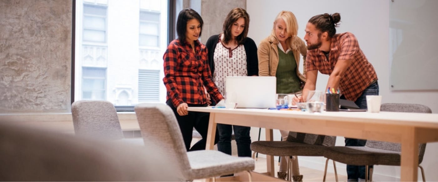 Team sharing knowledge around a laptop