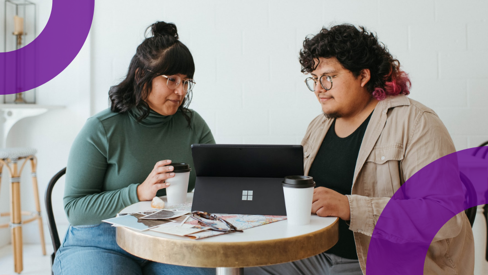 Two people lean over computer, exploring the design features of Valo Intranet