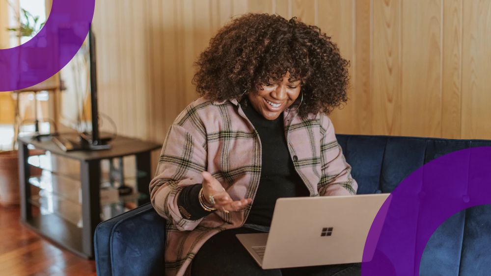 Woman wearing a check shirt is smiling at her laptop